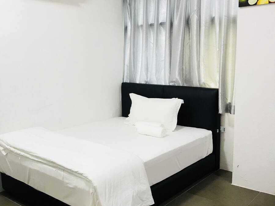Cama bem arrumada com lençóis brancos em quarto com cabeceira preta.