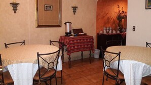 Un espace repas comprenant deux tables rondes, des chaises, un coin café et un tableau encadré accroché au mur.