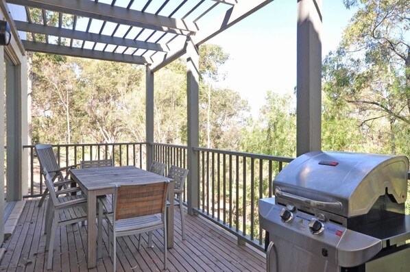 A covered outdoor deck with a grill and seating area.