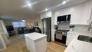 A modern kitchen with white cabinets, stainless steel appliances, and a marble countertop. - Island House Beach Resort V8 (Siesta Key)