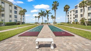 A courtyard with a central bench, two shuffleboard courts, and palm trees. - Island House Beach Resort V8 (Siesta Key)