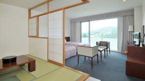 A hotel room with a bed, a desk, a chair, and a view of a lake. - Menard Aoyama Resort Hotel Schönvert (Iga)