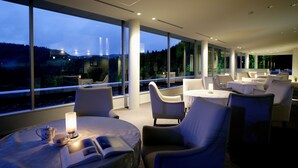 A modern hotel room with large windows, comfortable seating, and a view of the outdoors. - Menard Aoyama Resort Hotel Schönvert (Iga)