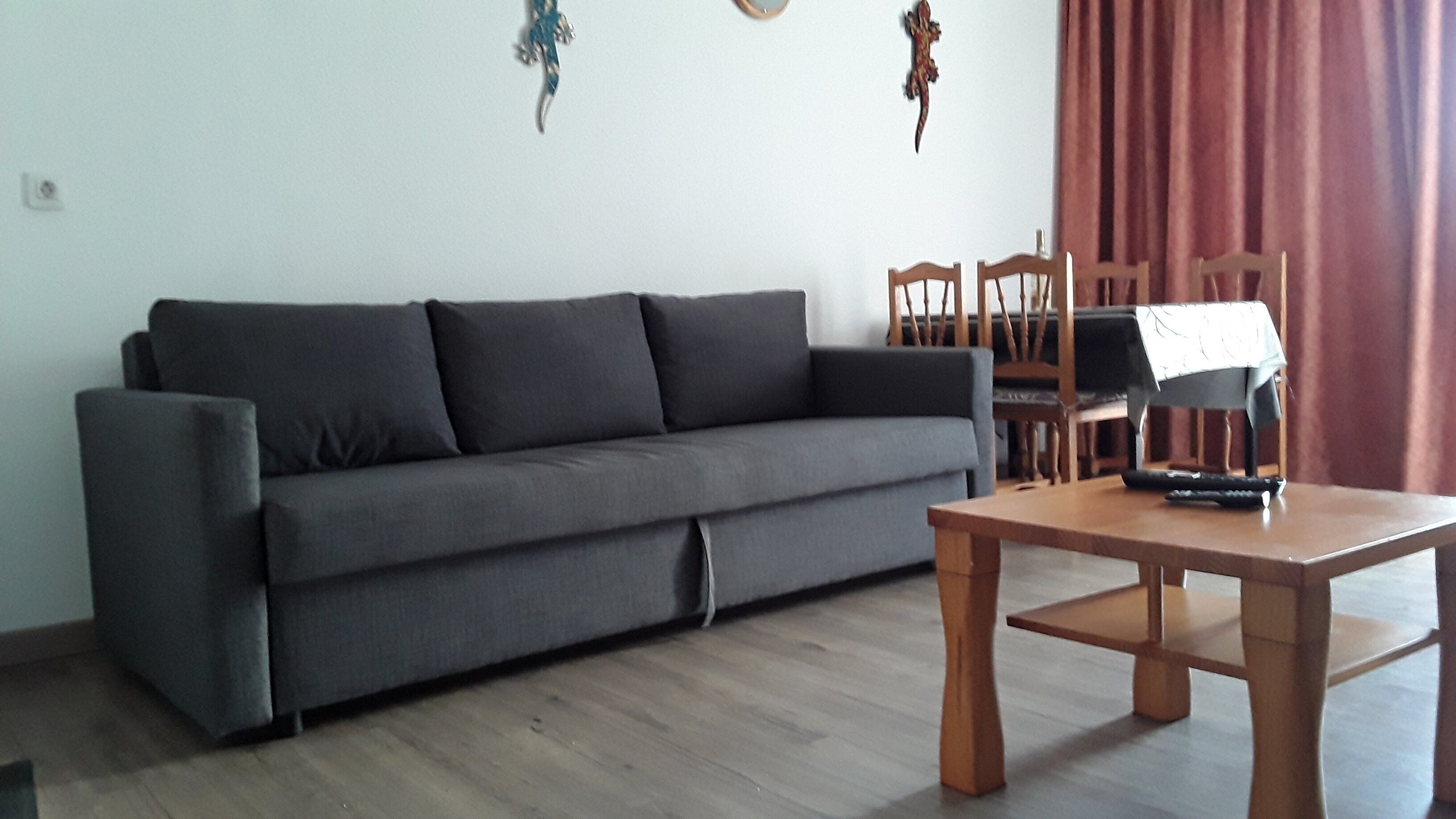 Ein Wohnzimmer mit grauem Sofa, einem Holzesstisch und Stühlen.
