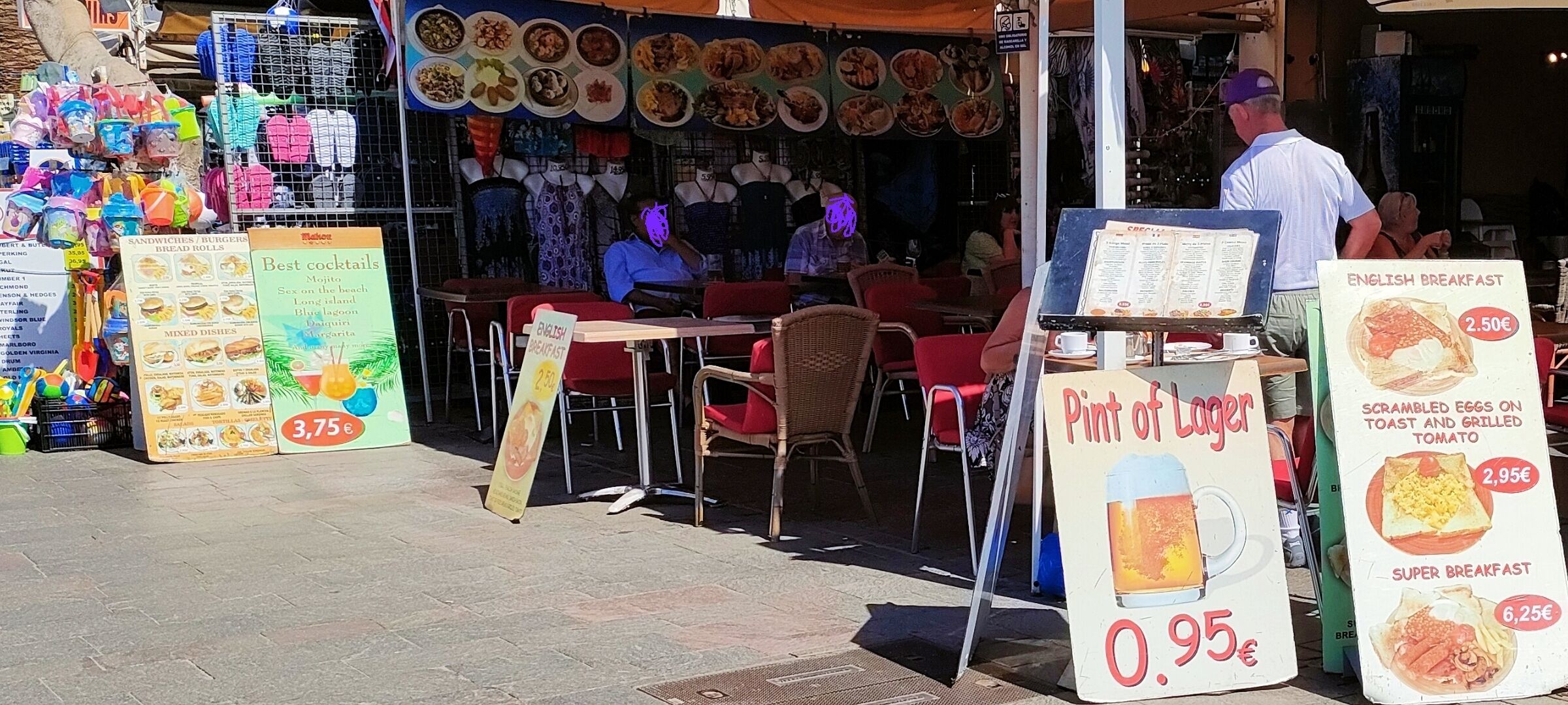 A food stall with various dishes displayed, a menu board, and a sign for a pint of lager.