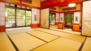 Una habitación tradicional japonesa con suelo de tatami, puertas correderas y techo de madera bajo.