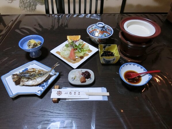 A dining table with various dishes, including fish, salad, and soup, along with chopsticks and a menu.