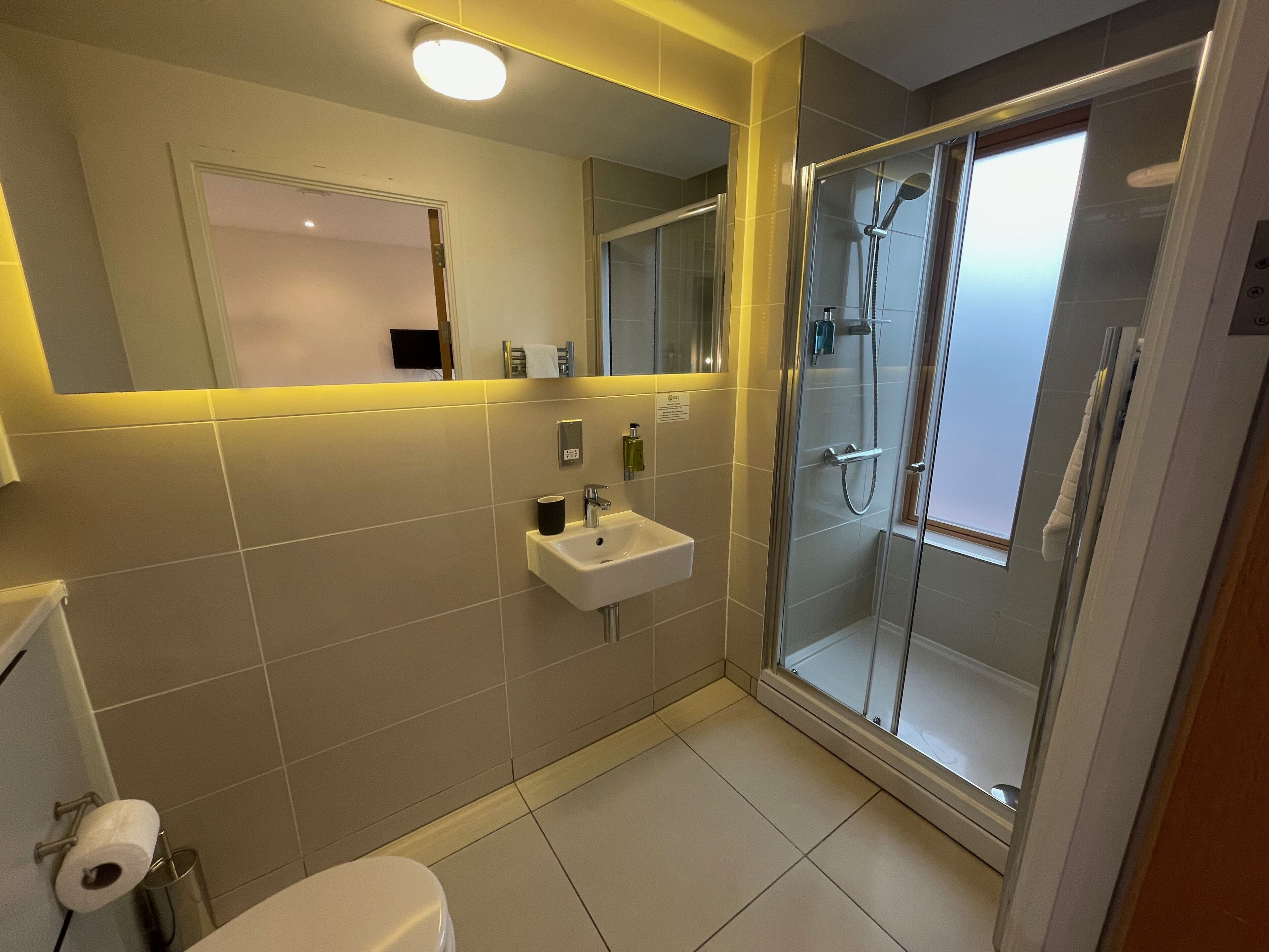 A modern bathroom with a glass-enclosed shower, a white sink, and a mirror above the sink.
