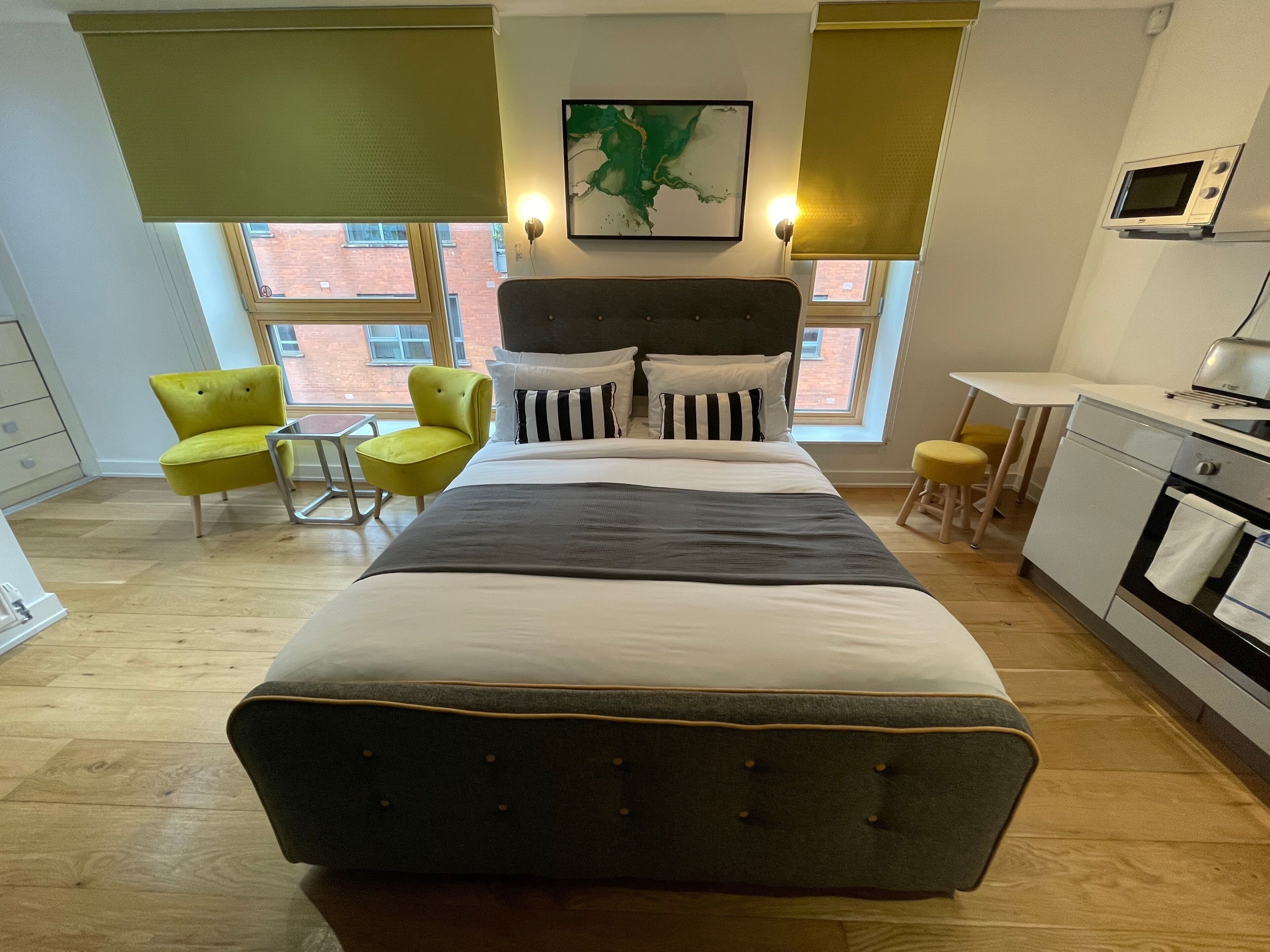 Une chambre moderne avec un grand lit, un bureau, une chaise et une vue sur l’extérieur.