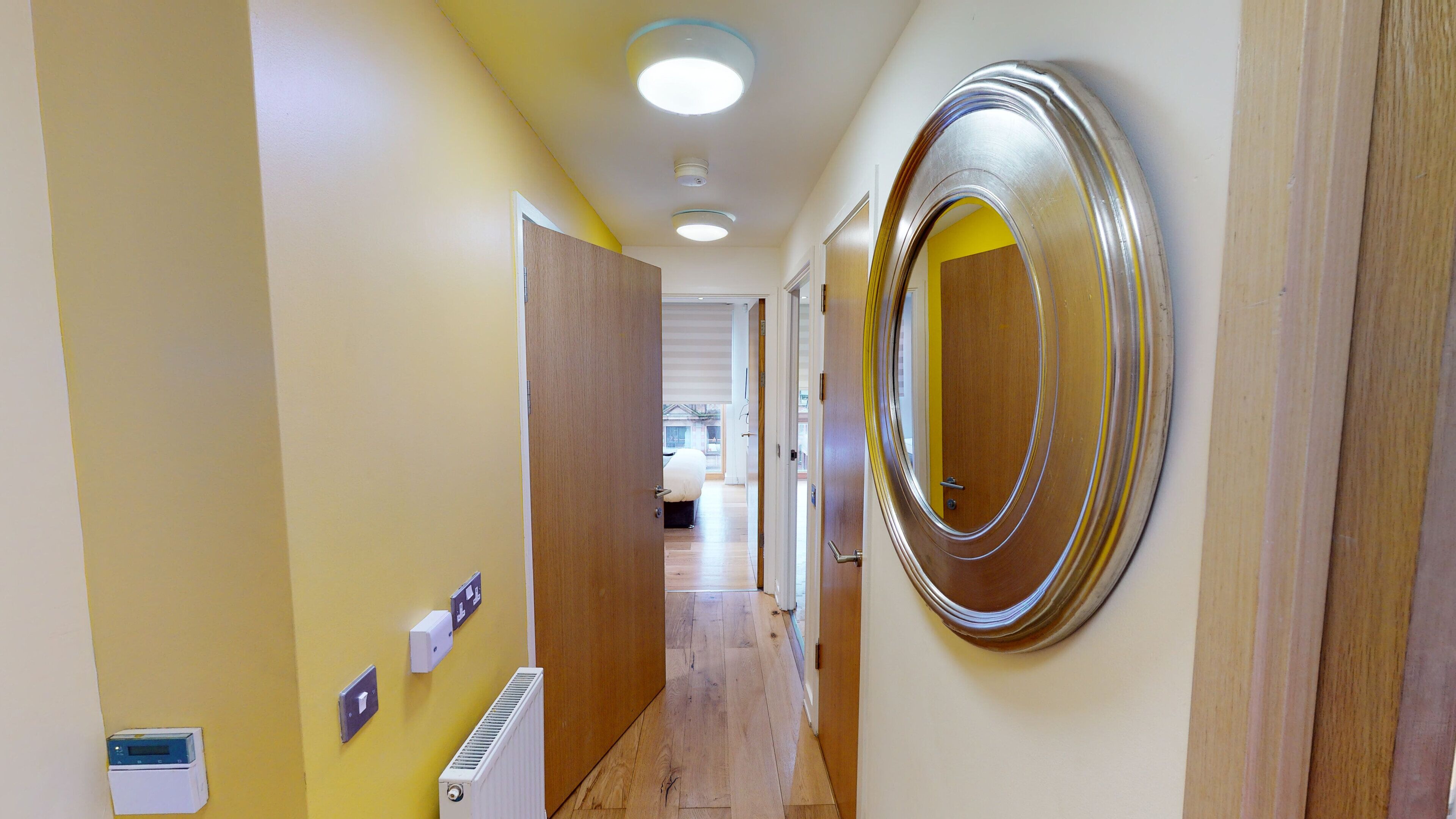 A hallway with a wooden door, a radiator, and a wall-mounted light fixture.