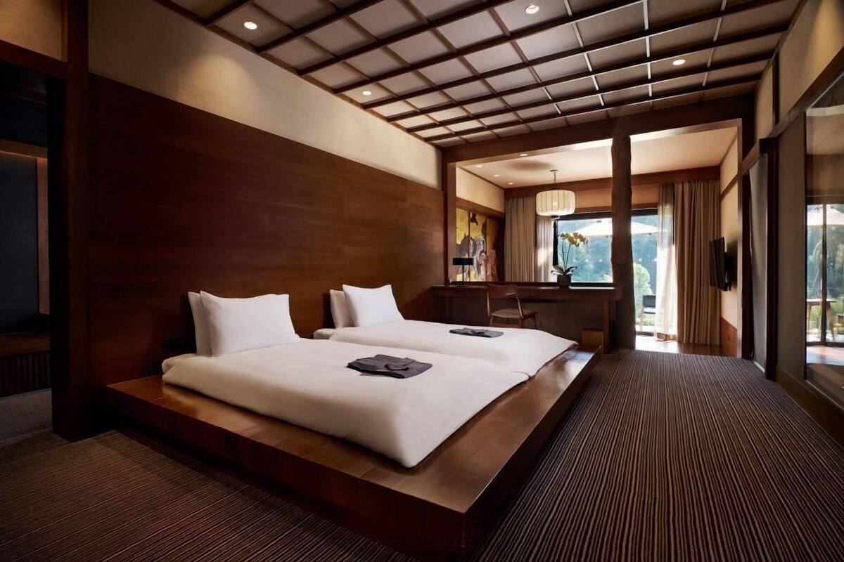 A hotel room with a large bed, a desk, and a view of the outdoors.