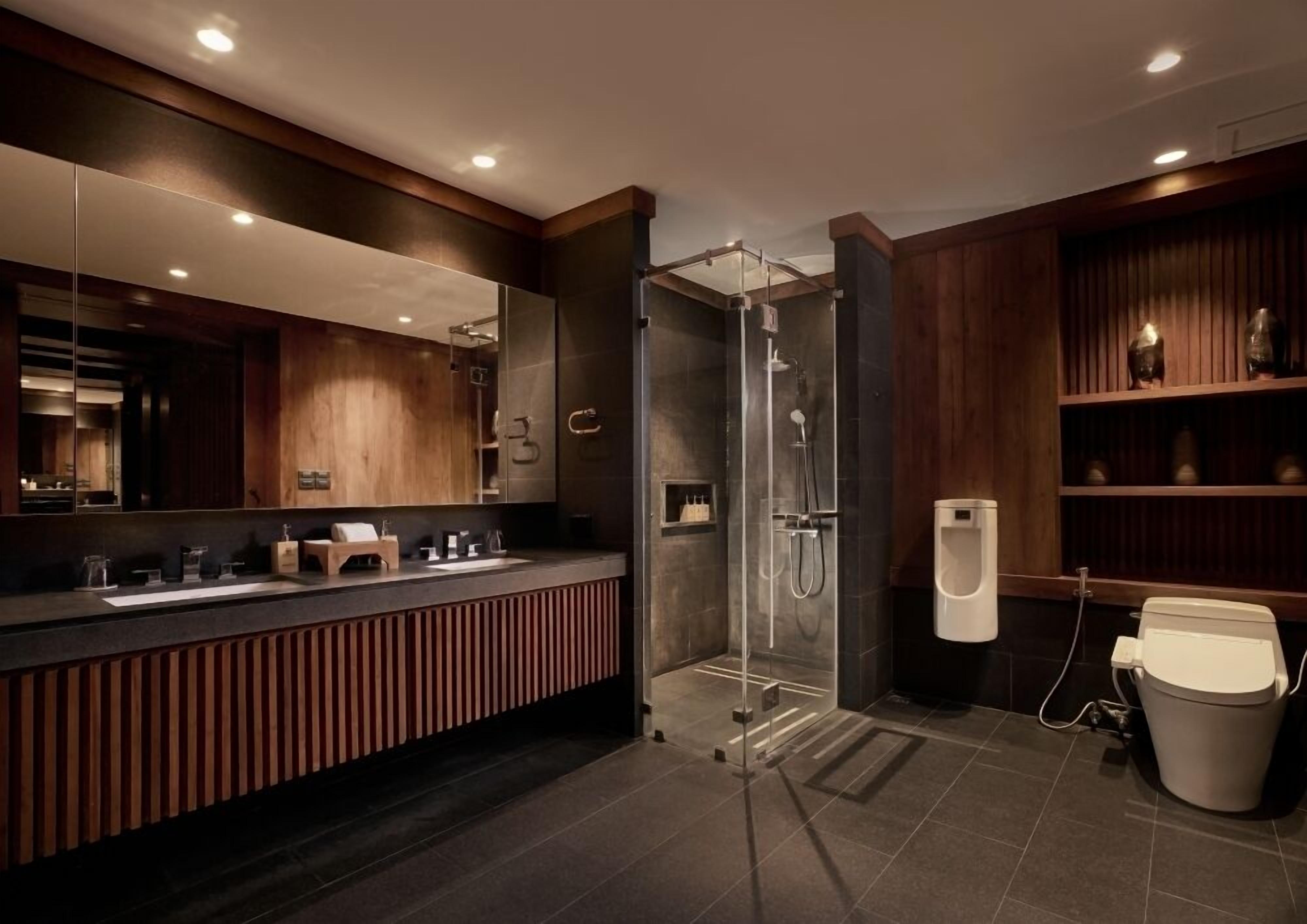 A modern bathroom with a glass-enclosed shower, a vanity with a mirror, and a toilet.