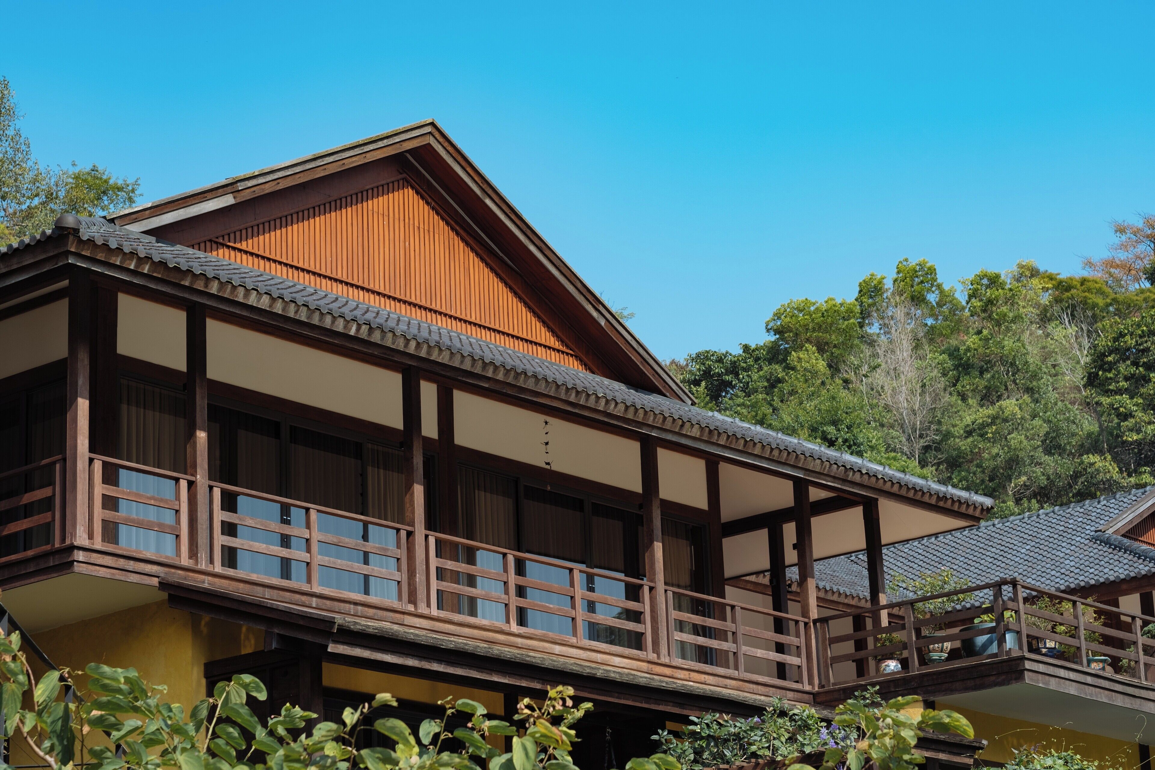 Un edificio de estilo japonés tradicional con fachada de madera, ventanas grandes y un balcón.
