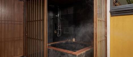 A spa area with a hot tub, steam, and a wooden door.