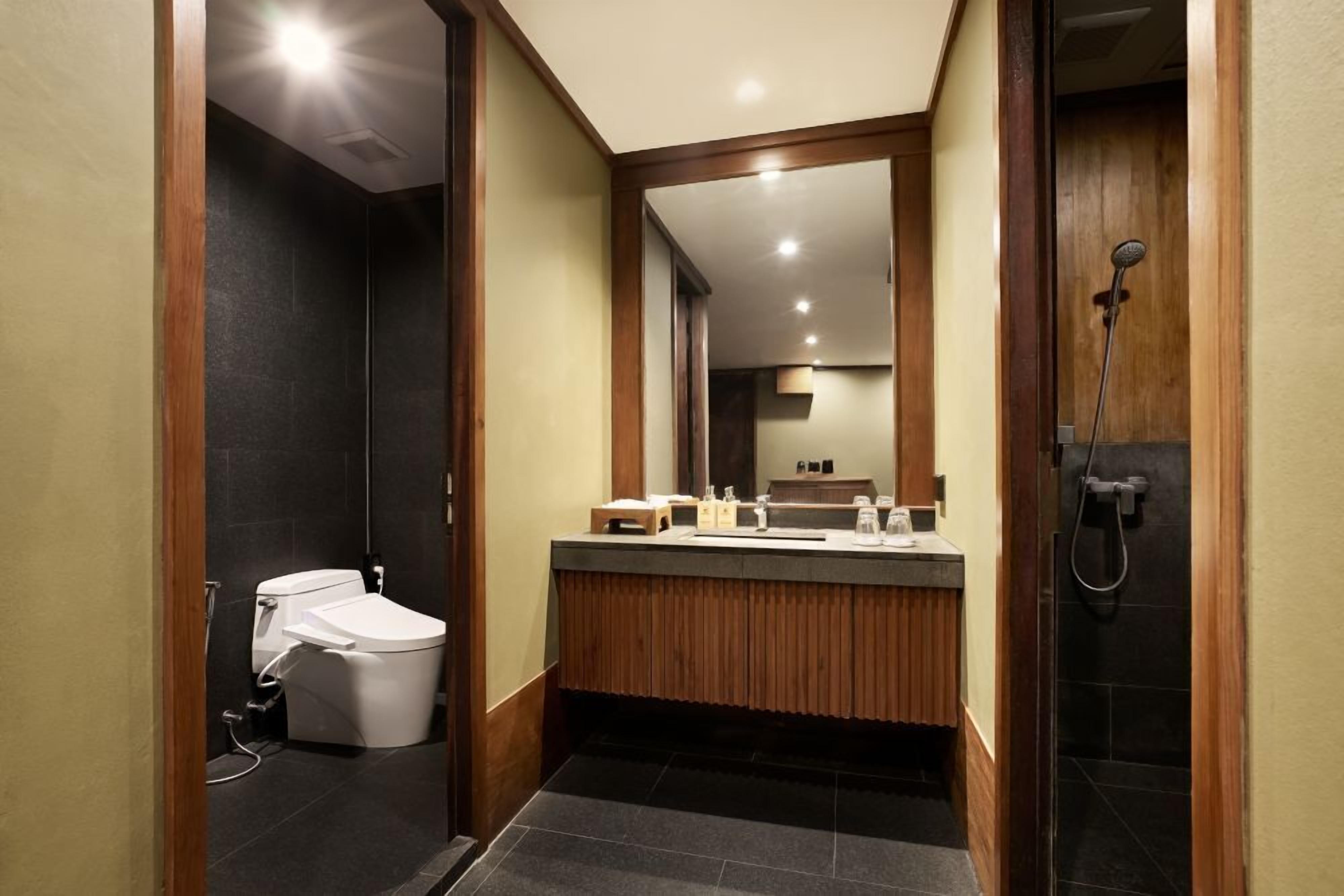 Un baño moderno con inodoro, lavabo, espejo y ducha.