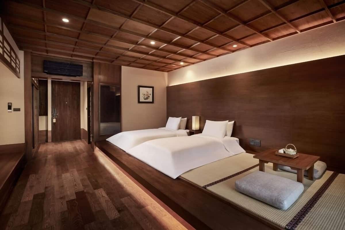 A hotel room with a wooden ceiling, two beds, a small table with a tray, and a picture on the wall.