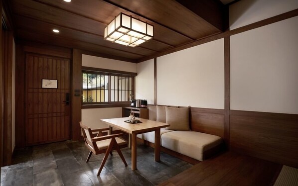 A traditional Japanese room with tatami flooring, a low table with a tea set, a sofa, and a shoji screen door. - Onsen At Moncham (Mae Rim)