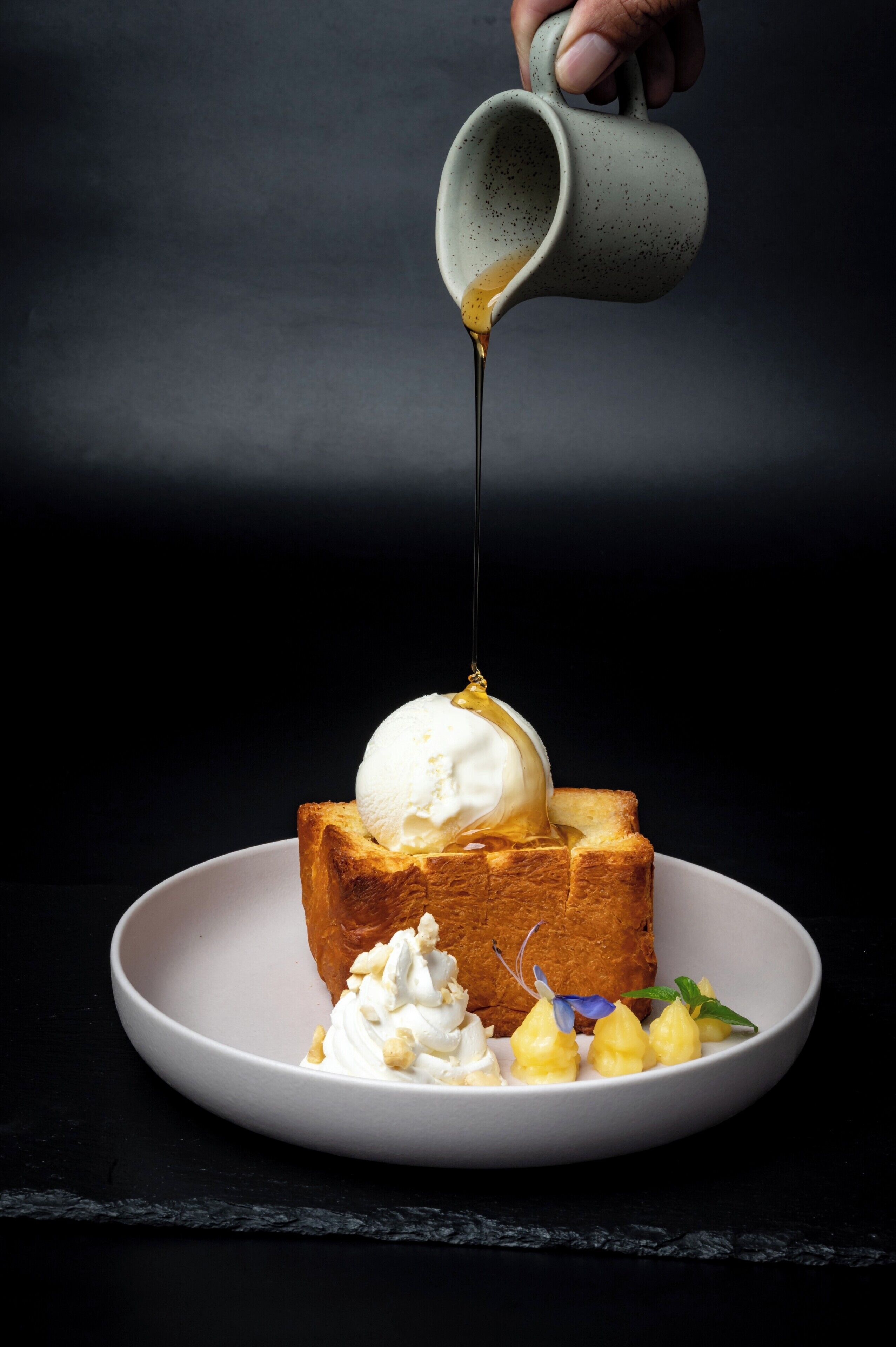 A dessert with ice cream, whipped cream, and syrup on toast, served on a plate.