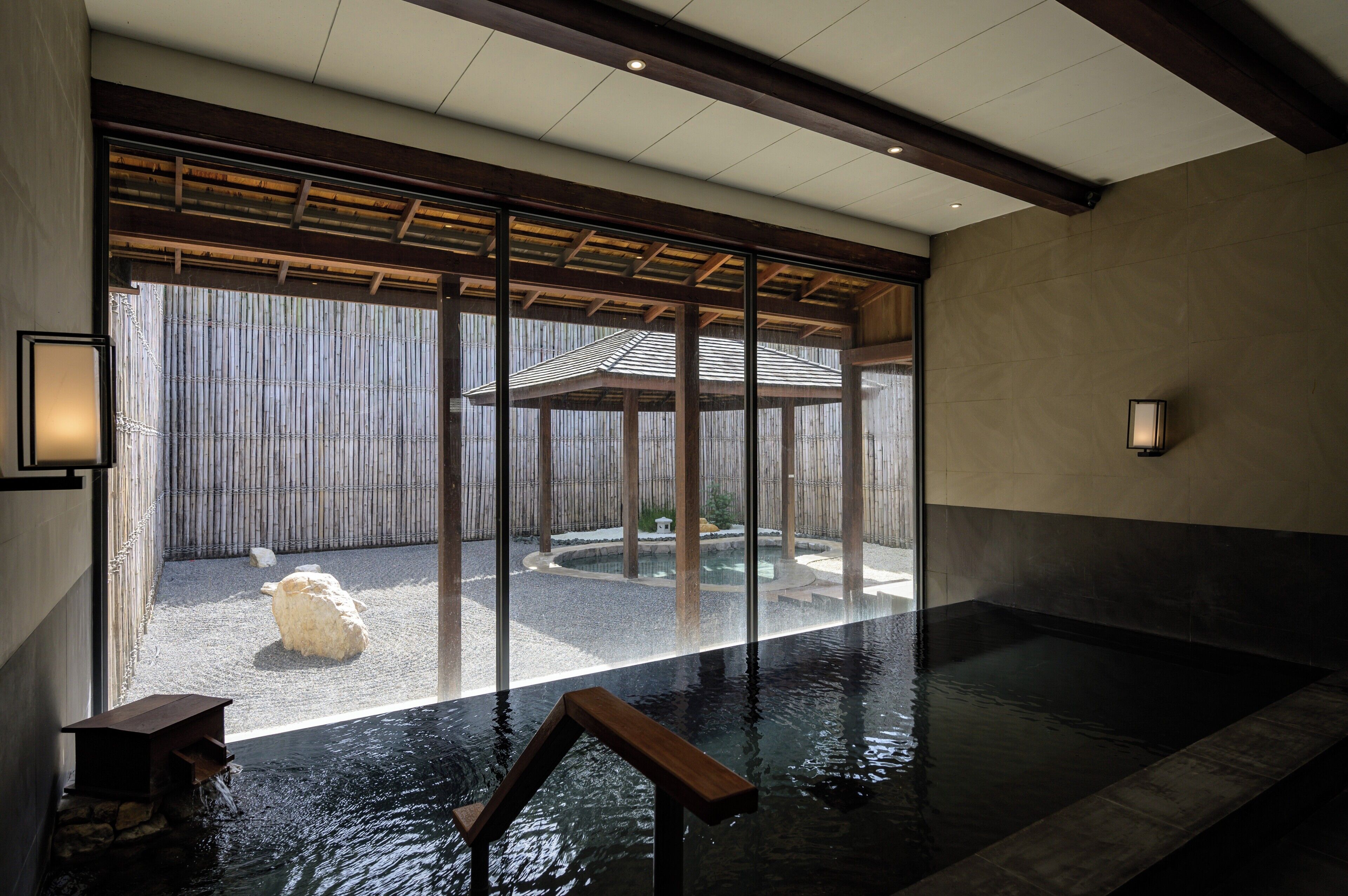 A serene indoor pool area with a view of a traditional Japanese garden through large sliding doors.
