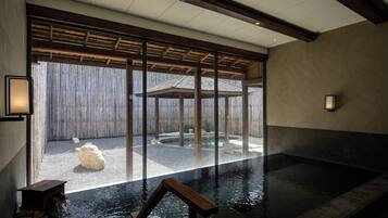Un área de piscina interior tranquila con vistas a un jardín japonés tradicional a través de amplias puertas correderas.