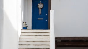 Un edificio blanco con una puerta azul y un conjunto de escalones blancos que conducen a una puerta de madera.