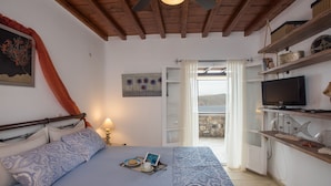 Un dormitorio con cama, mesita de noche y televisión.