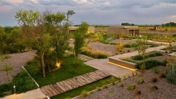 Un espacio exterior moderno con terraza de madera, jardín ajardinado y edificios contemporáneos.
