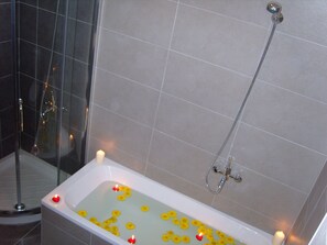 Een bad/douchecombinatie, een haardroger, handdoeken, toiletpapier