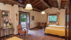 Une chambre rustique avec deux lits, un plafond en bois, une petite table avec une plante et une chaise.