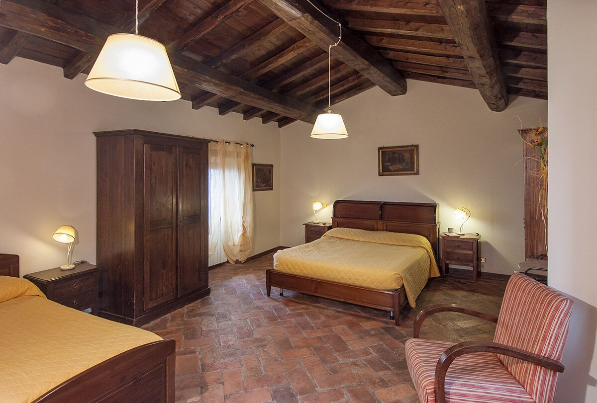 A bedroom with a wooden bed, a nightstand, a chair, and a wardrobe.