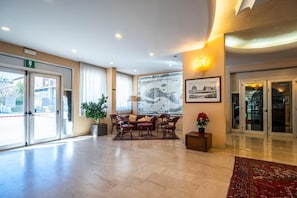 A hotel lobby with a reception desk, seating area, and a large wall map. - Albatros (CALENZANO)