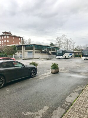 Un estacionamiento con un coche negro, un autobús y un edificio con escaleras.