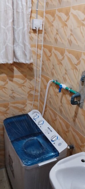 A bathroom with a tiled wall, a white sink, and a water heater.