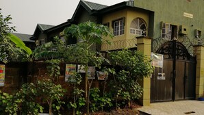 A building with a gated entrance, surrounded by greenery and various signs. - Entire, spacious, furnished 3beds en-suite, as holiday let with BrausengDelight (Lagos)