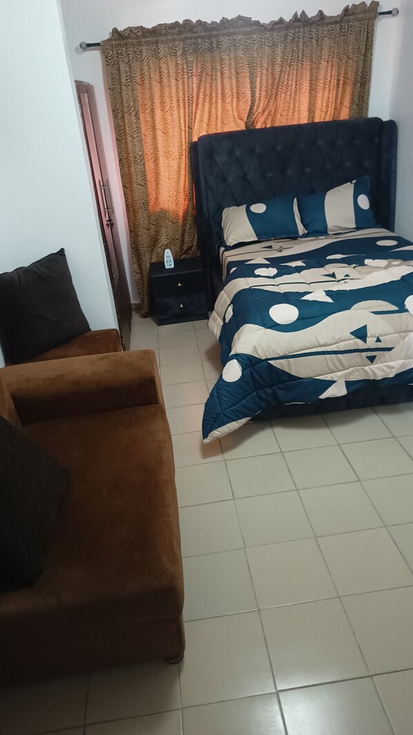 A bedroom with a bed, a brown sofa, and a nightstand.