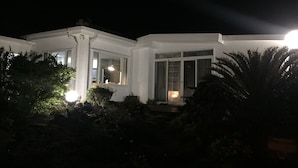 A two-story building with a white exterior, large windows, and a visible balcony. - Sunday Jeju (Seogwipo)