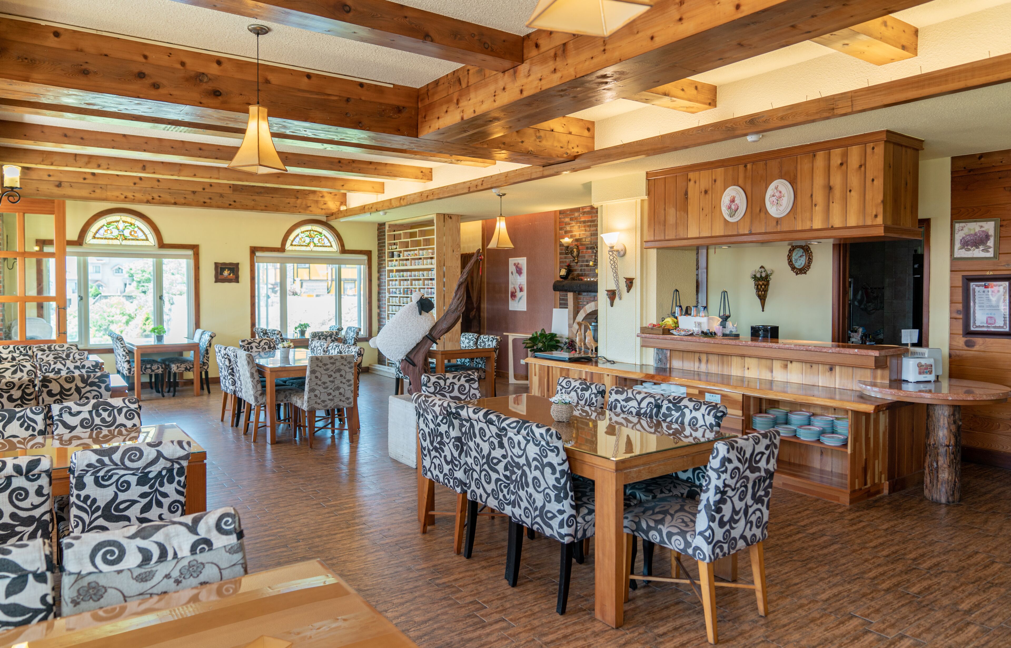 A spacious dining area with patterned chairs and a wooden table, a kitchen with wooden cabinets, and a staircase leading to another level.