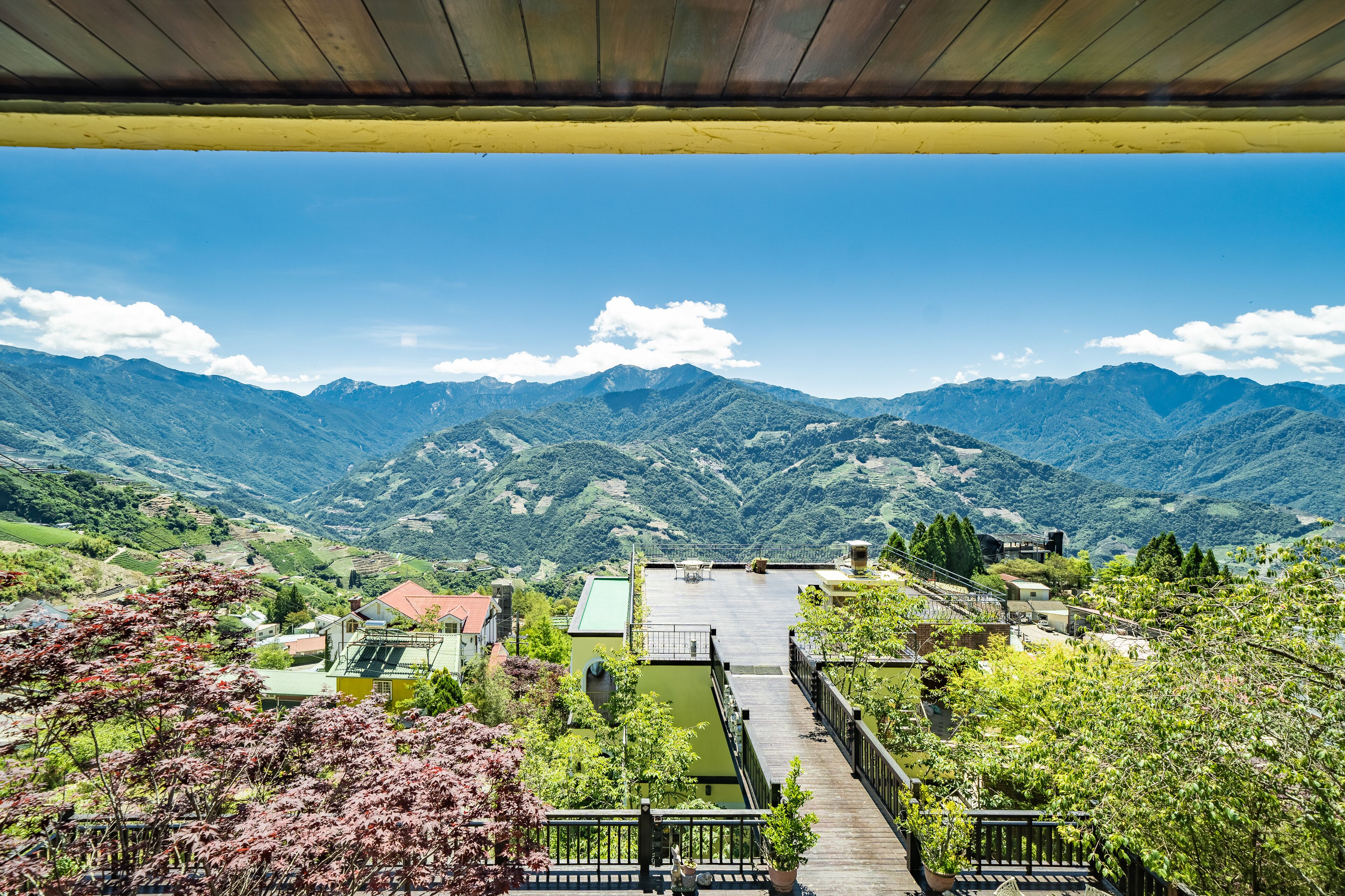 A view from a covered terrace overlooking a mountainous landscape with a wooden deck and a view of the valley below.