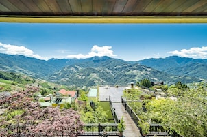 Vista desde una terraza cubierta con vista a un paisaje montañoso, un muelle de madera y el valle en la distancia.