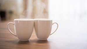 Dos tazas blancas de cerámica con asas sobre una superficie de madera.