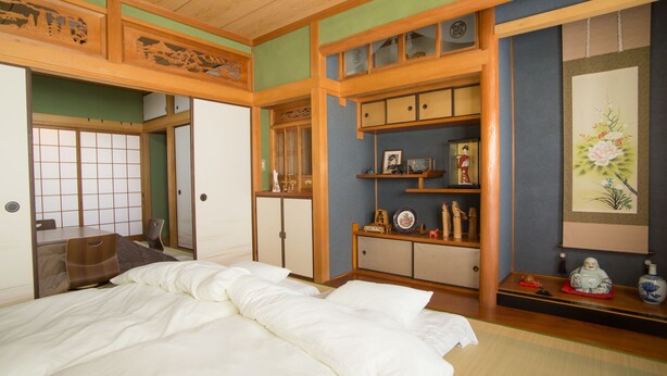 Una habitación tradicional japonesa con suelo de tatami, una cama baja de madera y puertas correderas shoji.