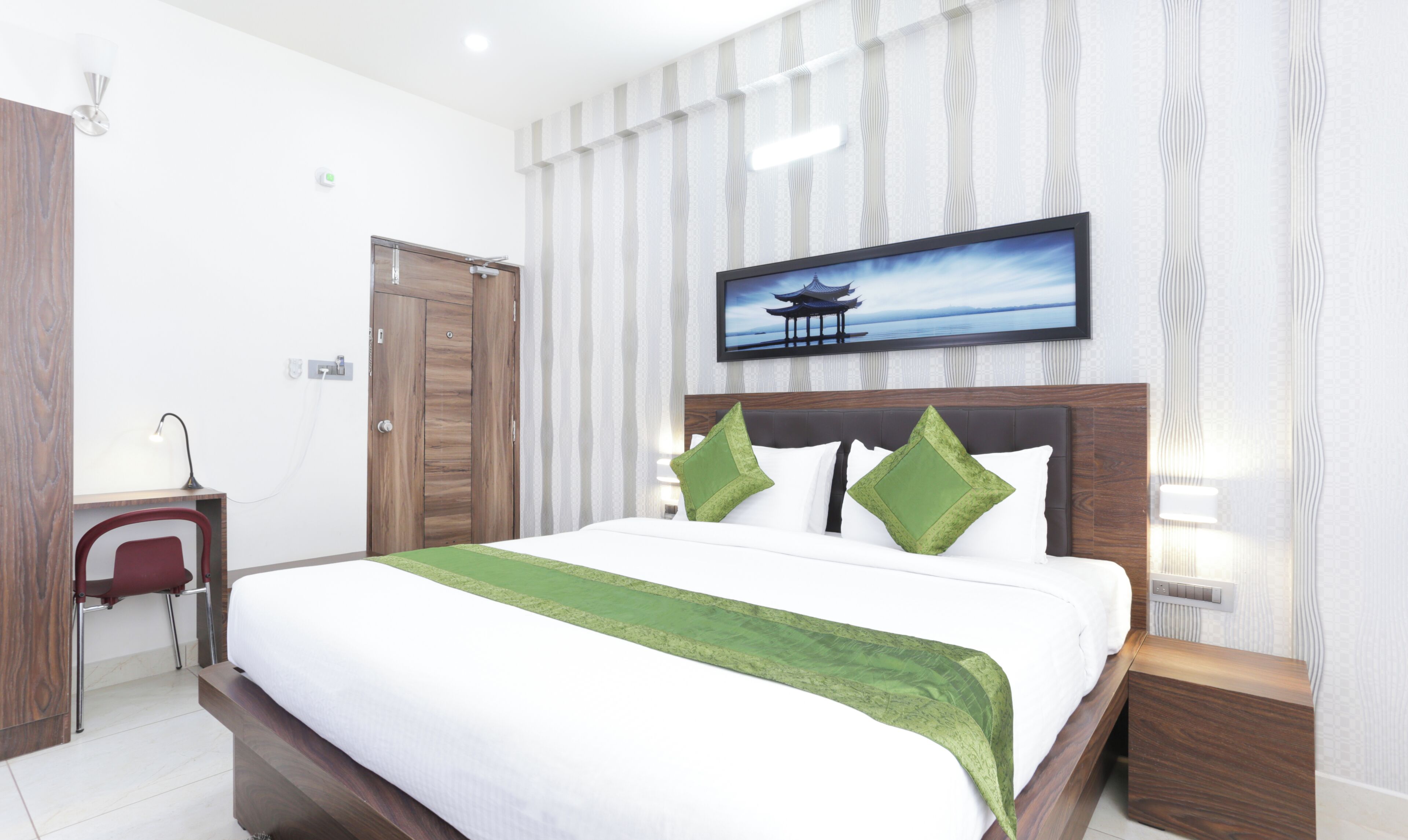 A hotel room with a bed, a desk, and a chair.
