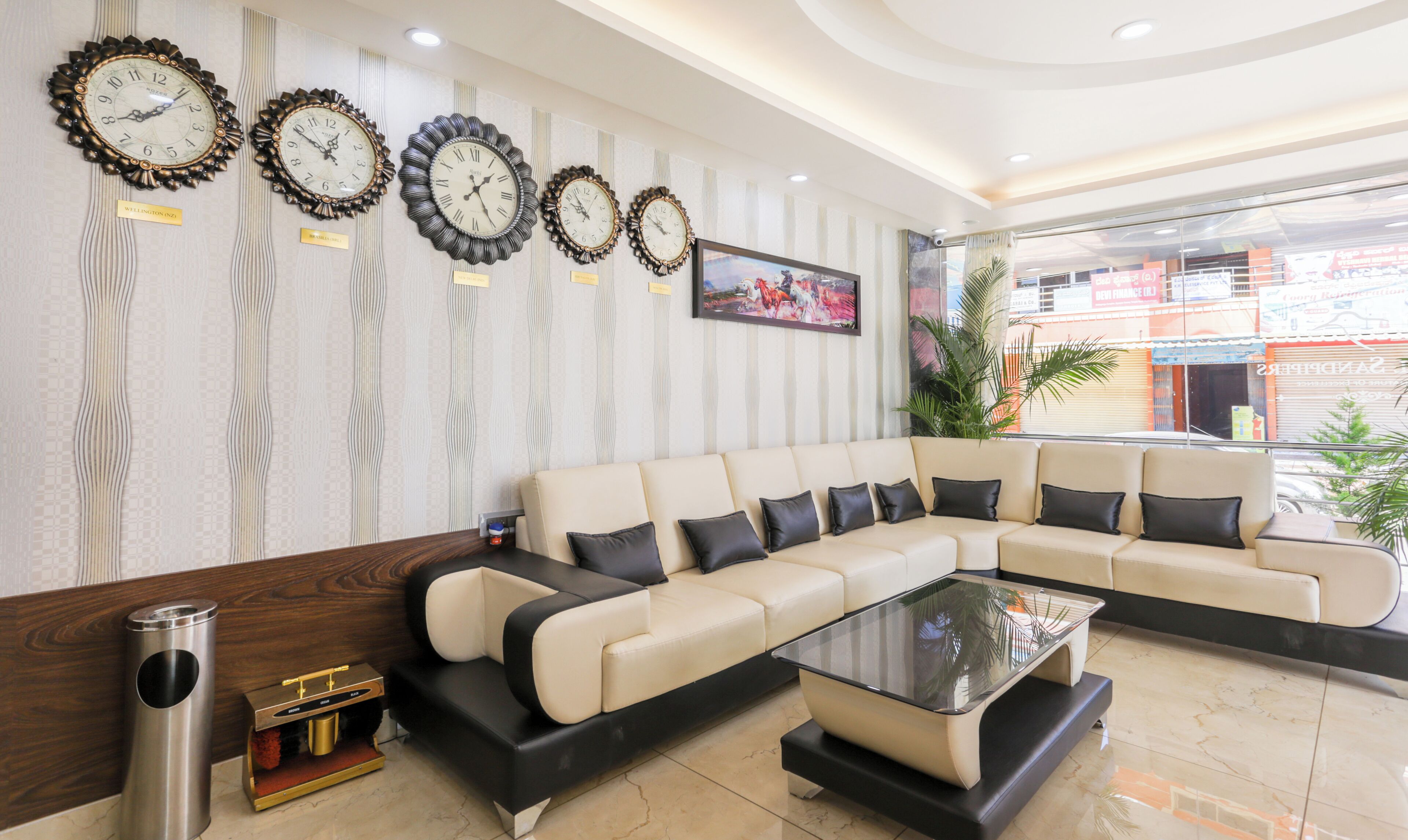 Eine moderne Lobby mit einem Ecksofa, einem Glastisch und dekorativen Wanduhren.