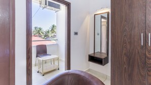 A bathroom with a wooden vanity, a mirror, and a small table with a chair. - Treebo Sandpipers Kushalnagar (Somvarpet)