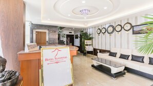 A hotel lobby with a reception desk, a white sofa, and a chandelier. - Treebo Sandpipers Kushalnagar (Somvarpet)