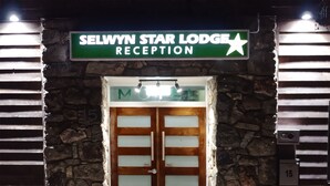La entrada a la recepción del Selwyn Star Lodge, con fachada de piedra y un letrero sobre las puertas.