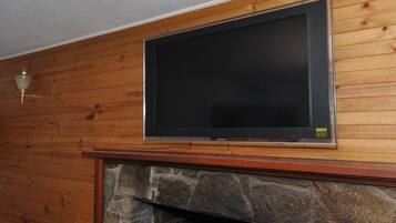 Un televisor de pantalla plana montado en una pared de madera sobre una chimenea de piedra.