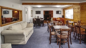 Una habitación acogedora con sofá, mesas de comedor, sillas, chimenea y televisor.