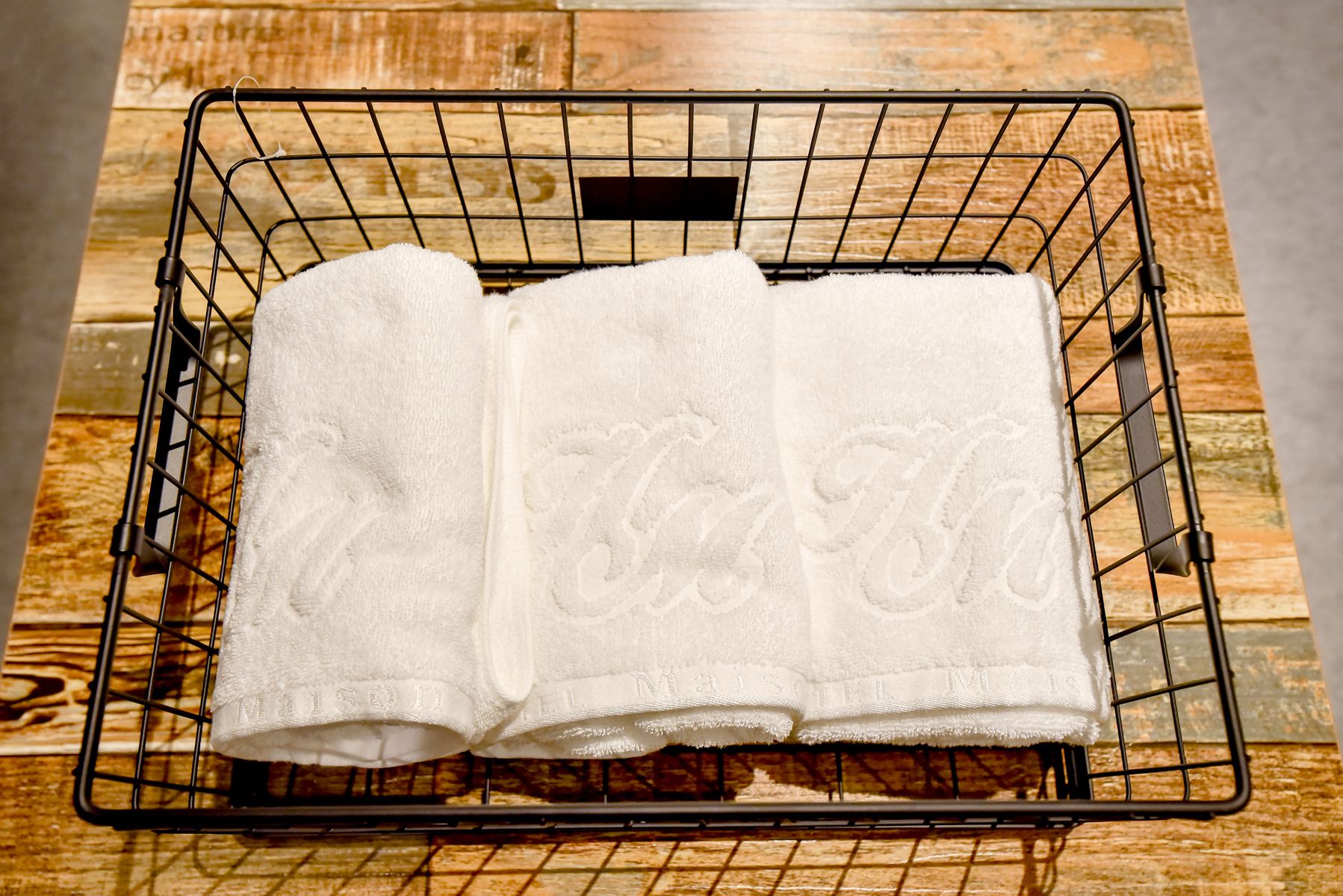 A metal drying rack with folded white towels on a wooden surface.