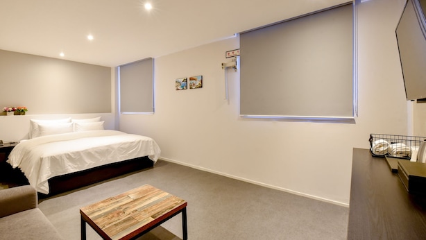 Ein modernes Schlafzimmer mit einem Bett, einem kleinen Tisch und einem großen Fenster.